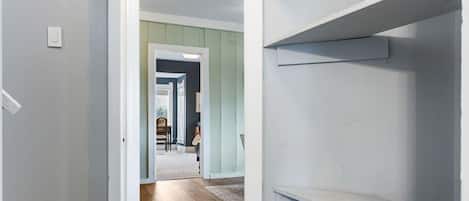 Un pasillo con piso de madera, una puerta blanca y una escalera con barandillas blancas.