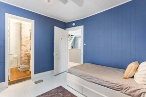 A bedroom with a bed, a door leading to a bathroom, and a mirror. - Farmhouse Retreat - 2 Acres, Fire Pit & Orchard Views (Fennville)