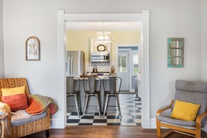 A kitchen with a checkered floor, a refrigerator, a microwave, and a dining area with chairs. - Farmhouse Retreat - 2 Acres, Fire Pit & Orchard Views (Fennville)
