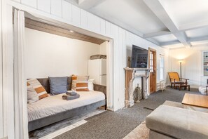 A cozy room with a bed, a fireplace, a chair, and a table. - Farmhouse Retreat - 2 Acres, Fire Pit & Orchard Views (Fennville)