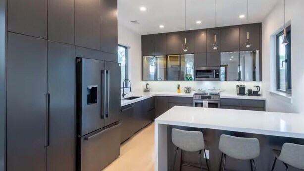 A modern kitchen with dark cabinetry, stainless steel appliances, and pendant lighting. - Downtown Escape | Modern Stay with Pool (Austin)