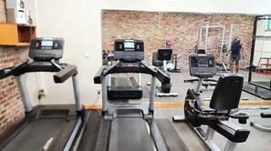 A gym with treadmills, a weight bench, and a brick wall. - Downtown Escape | Modern Stay with Pool (Austin)