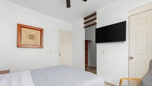 A bedroom with a bed, a chair, a TV, a wardrobe, and a door. - Peaceful and Fully-Equipped 3-Bedroom Retreat (Bucerías)