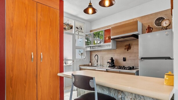 A modern kitchen with wooden cabinets, a marble countertop, and a stove. - Peaceful and Fully-Equipped 3-Bedroom Retreat (Bucerías)