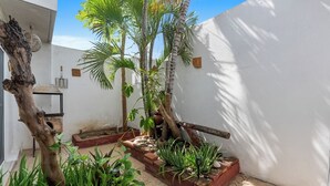 A courtyard with a wooden tree, potted plants, and a brick planter. - Peaceful and Fully-Equipped 3-Bedroom Retreat (Bucerías)