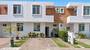 A modern two-story building with a central entrance, potted plants, and a paved driveway. - Peaceful and Fully-Equipped 3-Bedroom Retreat (Bucerías)