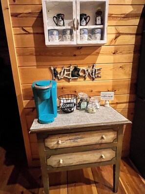 A wooden wall with a coffee station, including a blue coffee maker, a basket labeled 'COFFEE,' and a sign that reads 'WELCOME TO THE coffee nook.' - Easily Accessible charming 2bd 2ba cabin in Murphy, NC (Murphy)