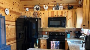 Eine Küche mit Holzschränken, einem schwarzen Kühlschrank, einer Mikrowelle und einer Arbeitsplatte aus Granit.