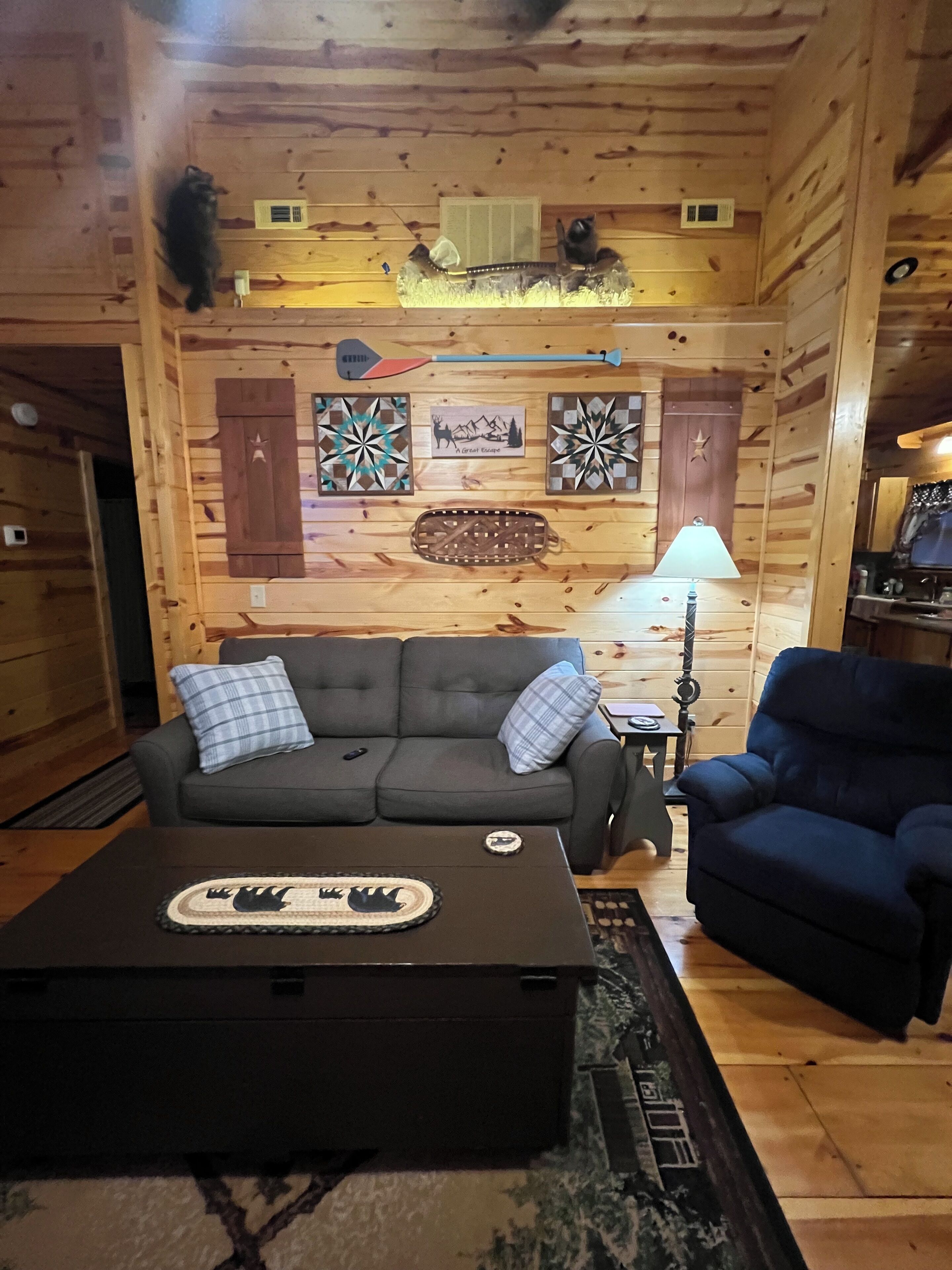 Ein gemütliches Blockhäuschen-Interieur mit einer Couch, einem Sessel und einem Couchtisch.