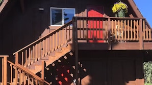 A wooden building with a balcony, a red door, and a window.
