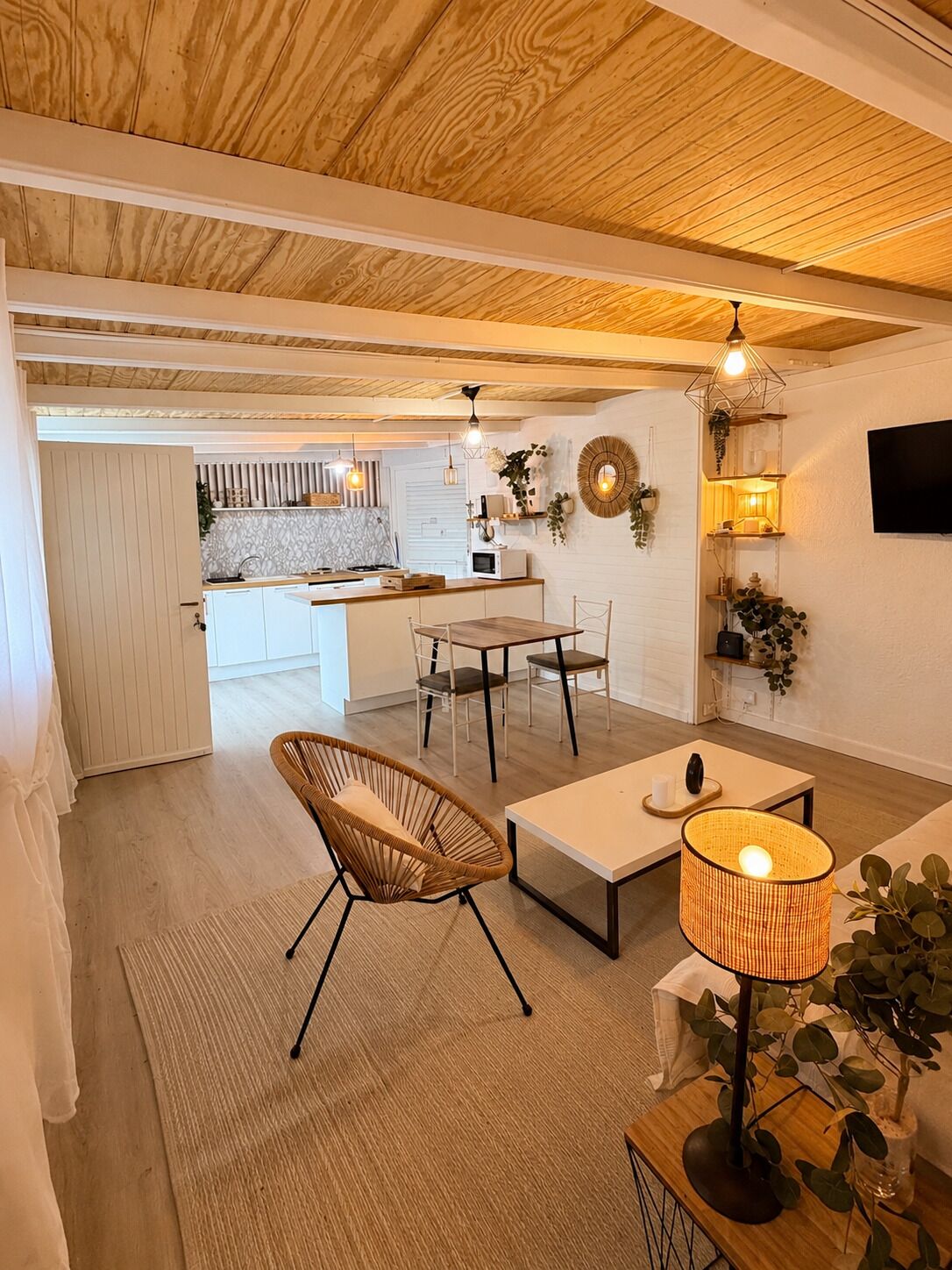 A modern kitchen with white cabinets, a wooden countertop, and a dining area with a table and chairs.