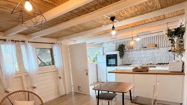 Et moderne køkken med hvide skabe, en træbordplade og et spiseområde med et bord og stole.