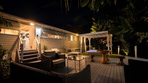En træterrasse med udendørs møbler, et boblebad og en pergola.
