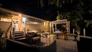 Eine Holzterrasse mit Gartenmöbeln, einem Whirlpool und einer Pergola.