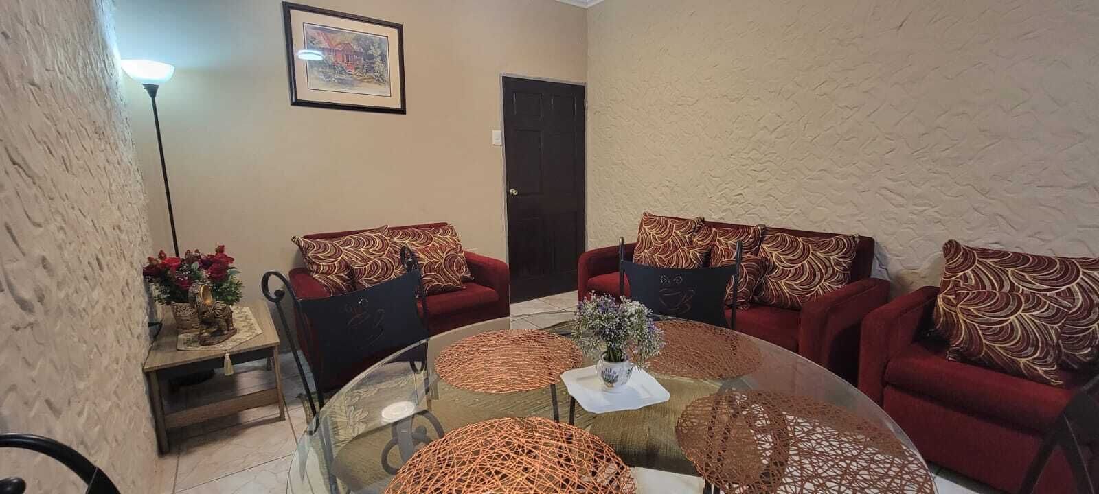A living room with two red sofas, a glass coffee table, and a framed picture on the wall.