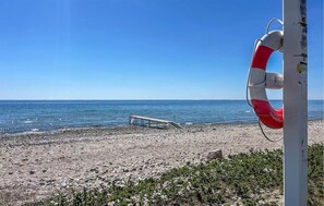 Ein Rettungsring an einem Pfahl, eine Holzkonstruktion am Strand und das Meer.