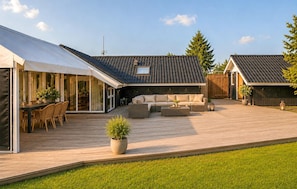 Ein moderner Außenbereich mit Terrasse, Sitzgelegenheit und überdachter Essbereich.