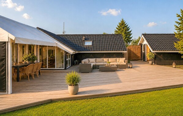 Een moderne buitenruimte met terras, zitgedeelte en een overdekte eethoek.