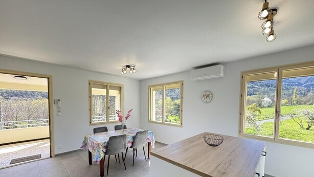 A spacious room with a dining table, chairs, a wooden countertop, large windows with a view, and ceiling lights. - Le Canigou - FUILLA - Vacation Rental (FUILLA)