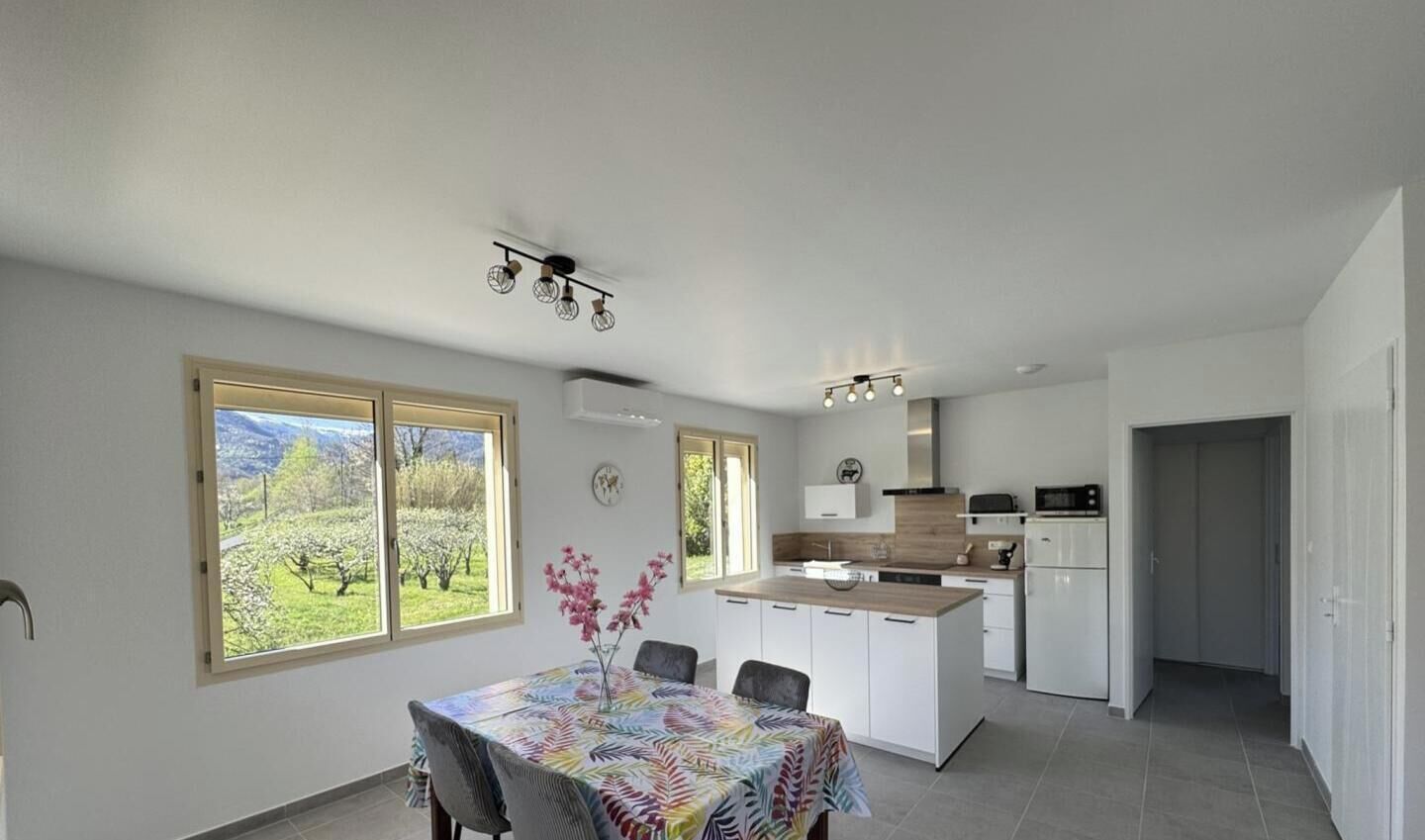 A modern kitchen with white cabinets, a central island, and a dining area with a table and chairs.