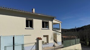 A two-story building with a balcony, a fenced area, and a clear sky. - Le Canigou - FUILLA - Vacation Rental (FUILLA)