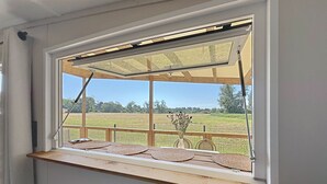 A window with a wooden ledge and a view of a green field. - Beach house with private parking - 4 guests (Saint-Pair-sur-Mer)