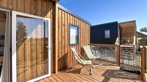 A wooden deck with a sliding glass door, a framed picture, and two lounge chairs. - Beach house with private parking - 4 guests (Saint-Pair-sur-Mer)