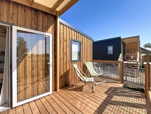 Eine Holzdielen-Terrasse mit einer Schiebetür, einem gerahmten Bild und zwei Loungesesseln.