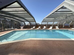 Ein Swimmingpool mit Liegestühlen und einer überdachten Terrasse.