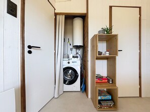 Ein Waschraum mit Waschmaschine, Wäscheständer und einer Holzablage mit Gesellschaftsspielen.