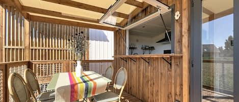 Un espacio al aire libre cubierto con una mesa, sillas, una cerca de madera y vistas hacia la casa.
