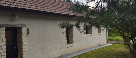 Un bâtiment d’un seul étage, doté d’un toit en tuiles, d’une entrée en pierre et d’un chemin pavé menant à la porte.