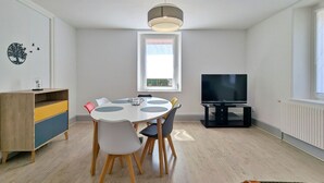 Un salon moderne comprenant une table à manger, des chaises, un téléviseur et une fenêtre donnant sur un beau paysage.