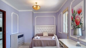 Ein Schlafzimmer mit einem Bett, einem Nachttisch, einer Lampe und Kunstwerken an der Wand.