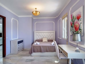 Ein Schlafzimmer mit einem Bett, einem Nachttisch, einer Lampe und Kunstwerken an der Wand.