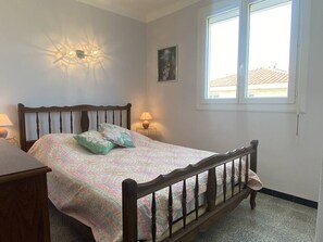 Ein Schlafzimmer mit einem hölzernen Bett, zwei Nachttischlampen, einem Fenster und einer Wandleuchte.