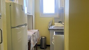 A compact kitchen with a refrigerator, sink, and window. - T2 apartment, clear view - 4 guests (Canet-en-Roussillon)
