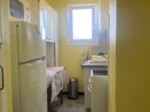 Eine kleine Küche mit Kühlschrank, Spüle und Fenster.