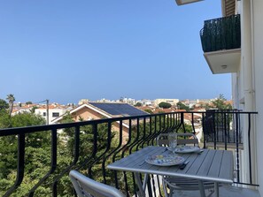 Ein Balkon mit Tisch und Stühlen mit Blick auf eine Wohngegend mit Häusern und Solaranlagen.