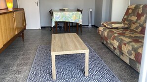 A living room with a sofa, a small table, a cabinet, a patterned rug, and a wall-mounted picture. - T2 apartment, clear view - 4 guests (Canet-en-Roussillon)