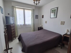 A bedroom with a bed, dresser, television, and two bedside lamps. - Central apartment with balcony - 4 guests (Fouras)