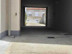 Ein Flur, der zu einem Gebäude mit einem Ziegeldach, einer weißen Wand und einer Metalttür führt.