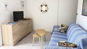 Un salon avec un téléviseur, un meuble en bois et un canapé à rayures.