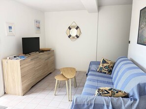 A living room with a TV, wooden cabinet, and a striped sofa. - T2 with private garden, calm - 4 guests (Saint-Georges-de-Didonne)