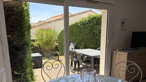 Une pièce avec une table dressée pour le repas, un barbecue à l’extérieur et un téléviseur posé sur un meuble en bois.