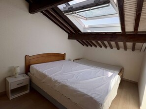 A bedroom with a skylight, a wooden headboard, a single bed, a bedside table with a lamp, and a small drawer. - House with AC, pool, parking - 5 guests (Argelès-sur-Mer)