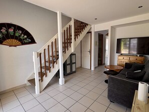 A living room with a staircase, a television, a sofa, and a decorative fan. - House with AC, pool, parking - 5 guests (Argelès-sur-Mer)