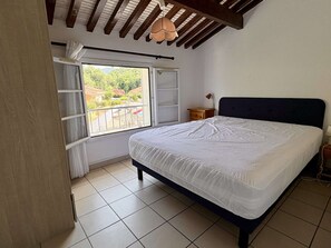 A bedroom with a bed, a window with curtains, a nightstand, and a ceiling fan. - House with AC, pool, parking - 5 guests (Argelès-sur-Mer)