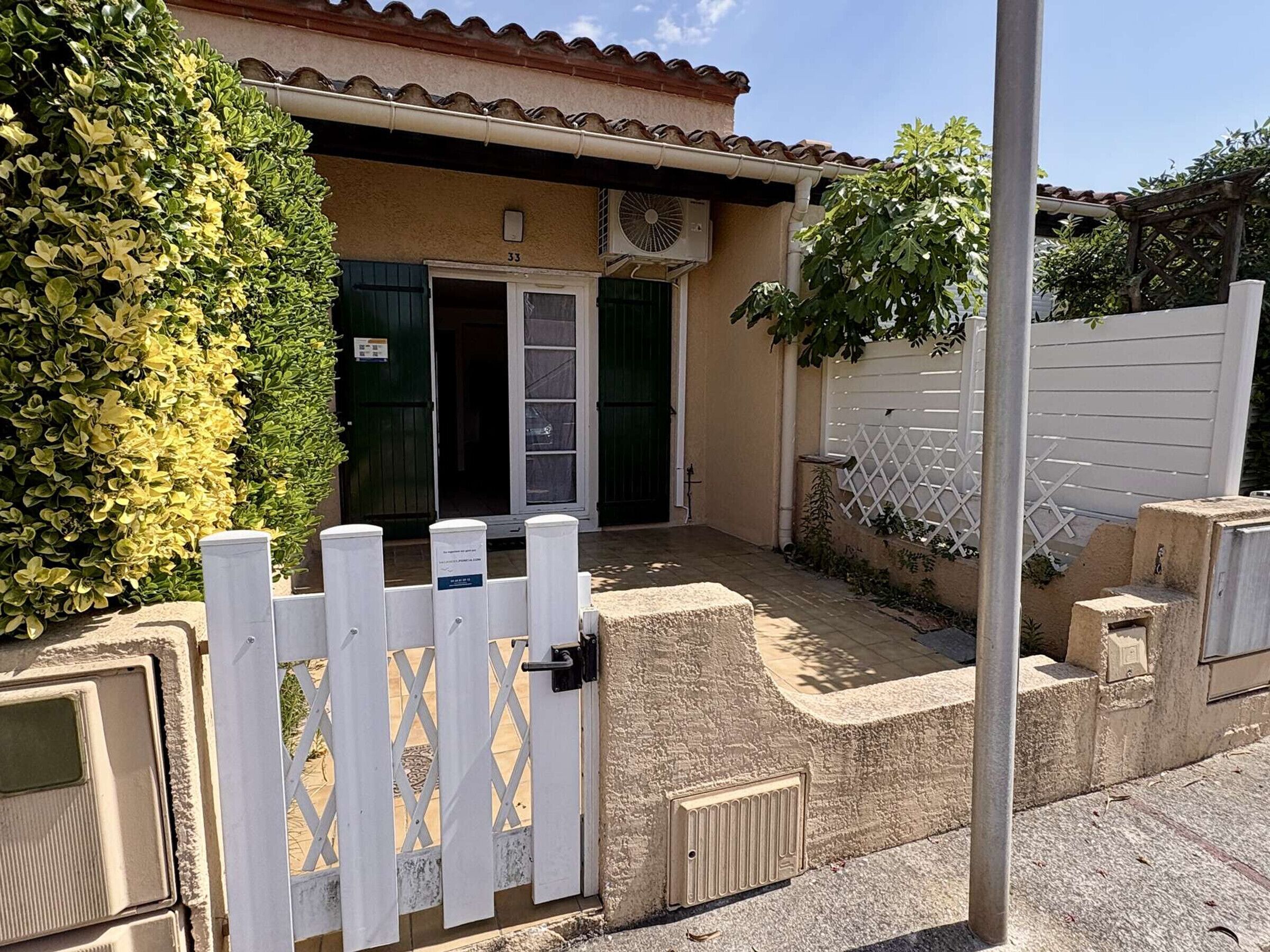 Un edificio con puerta numerada, cerca blanca y un pequeño jardín.