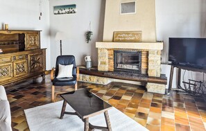 Una sala de estar con chimenea, televisor y un mueble de madera.